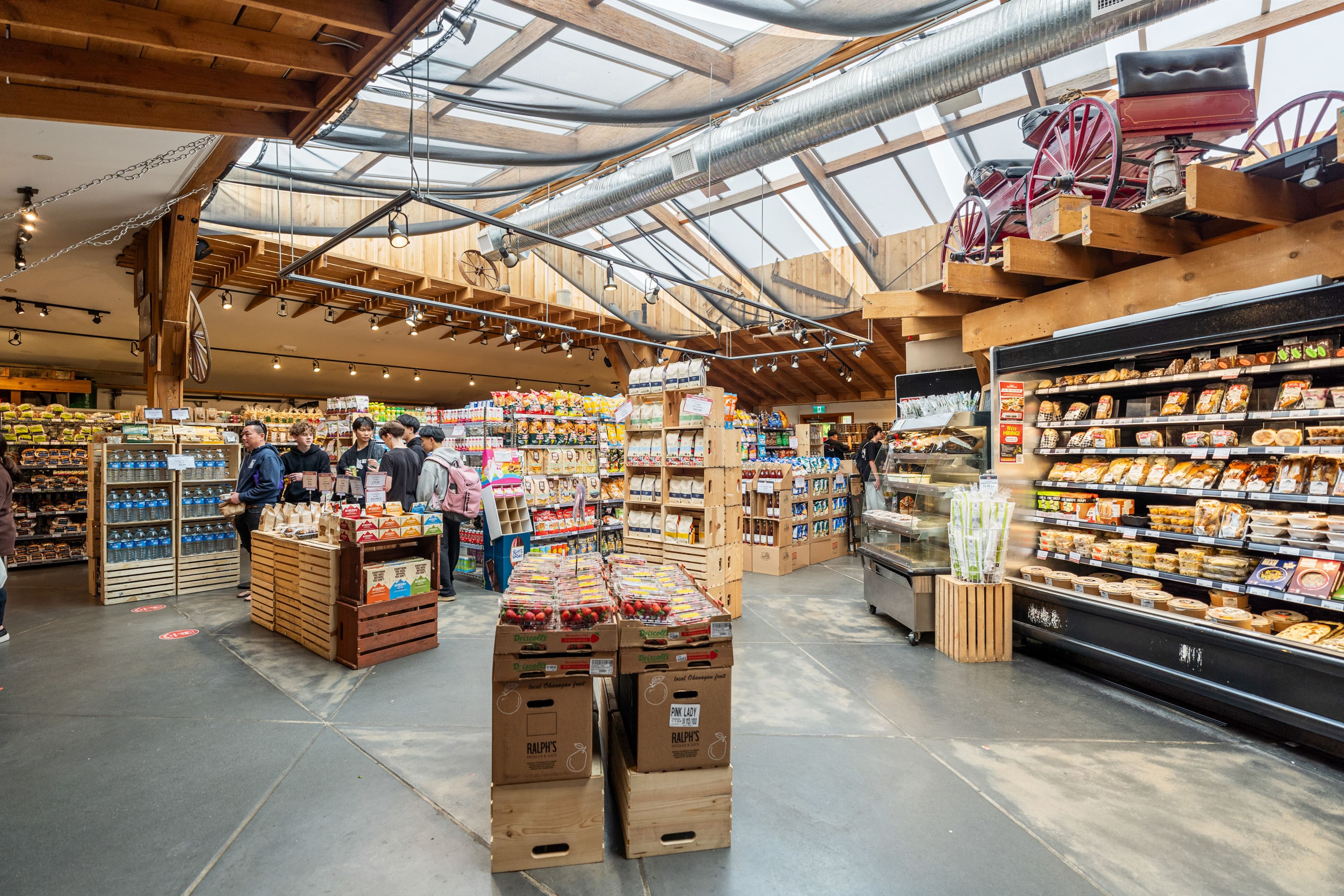Wide view of Red Barn Market interior with skylights, wood beams and a vintage horse-cart wheel display