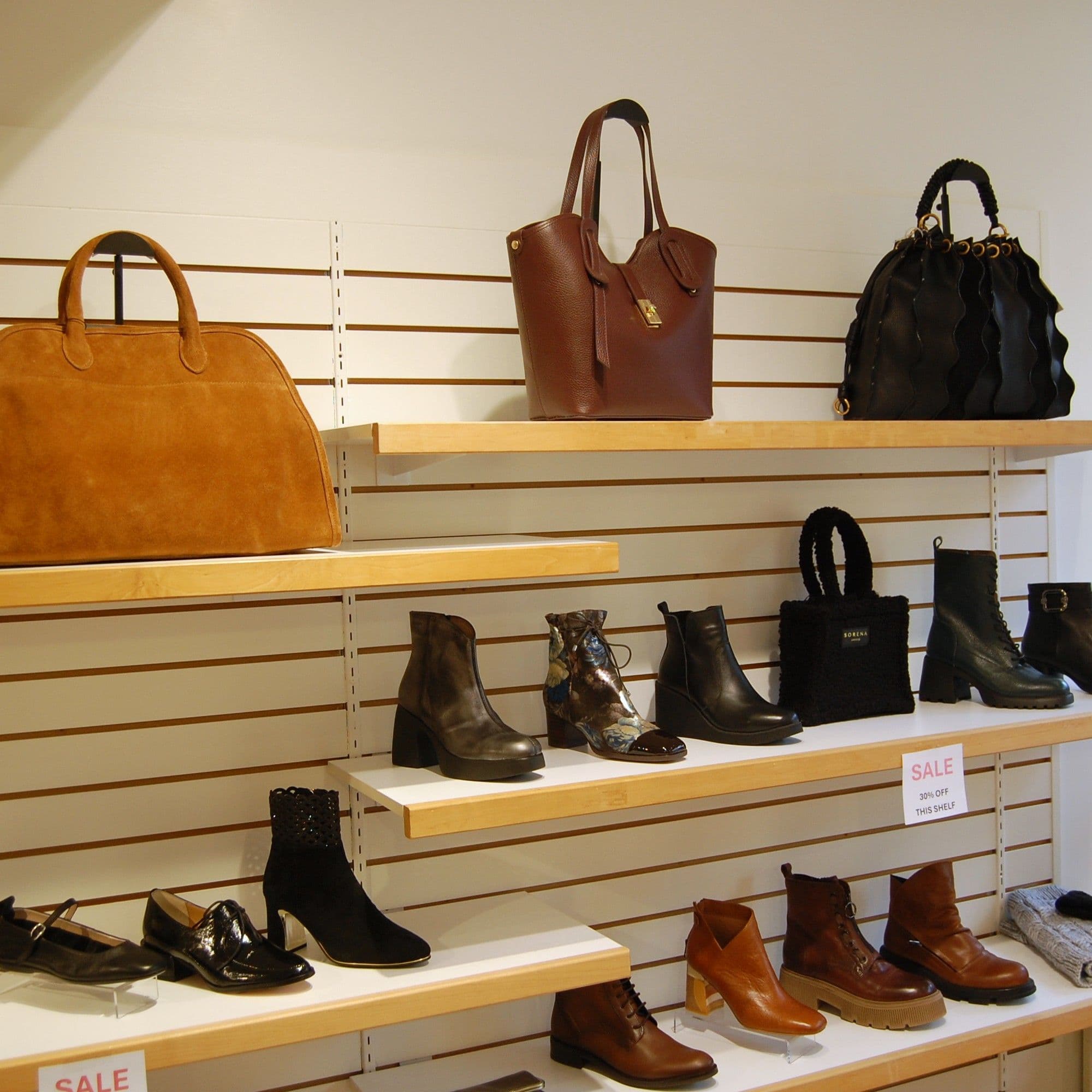 Bags and ankle boots styled together on slatwall shelves