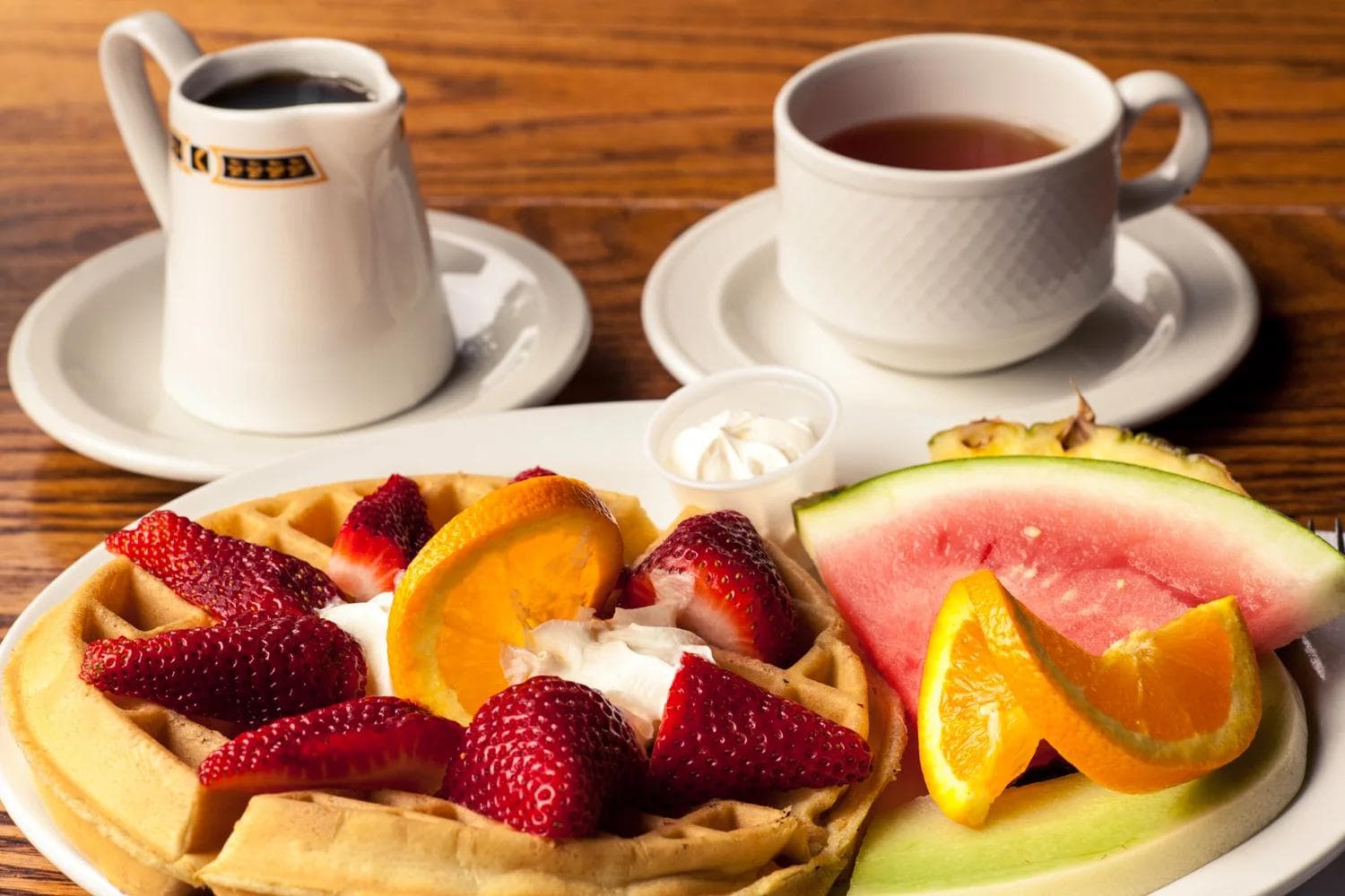 Waffle plate with strawberries, watermelon, tea and syrup