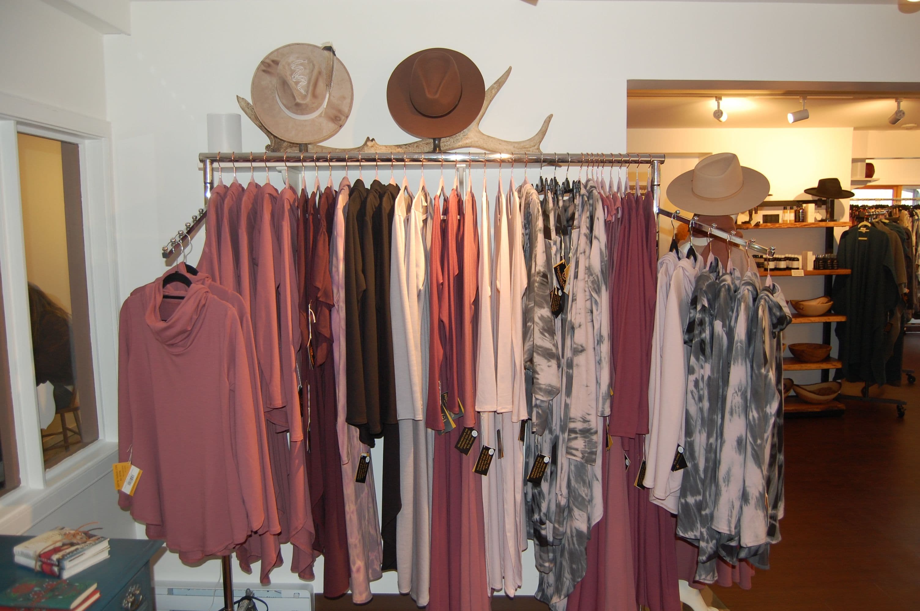 Garment rack in pinks and greys topped with cowboy hats