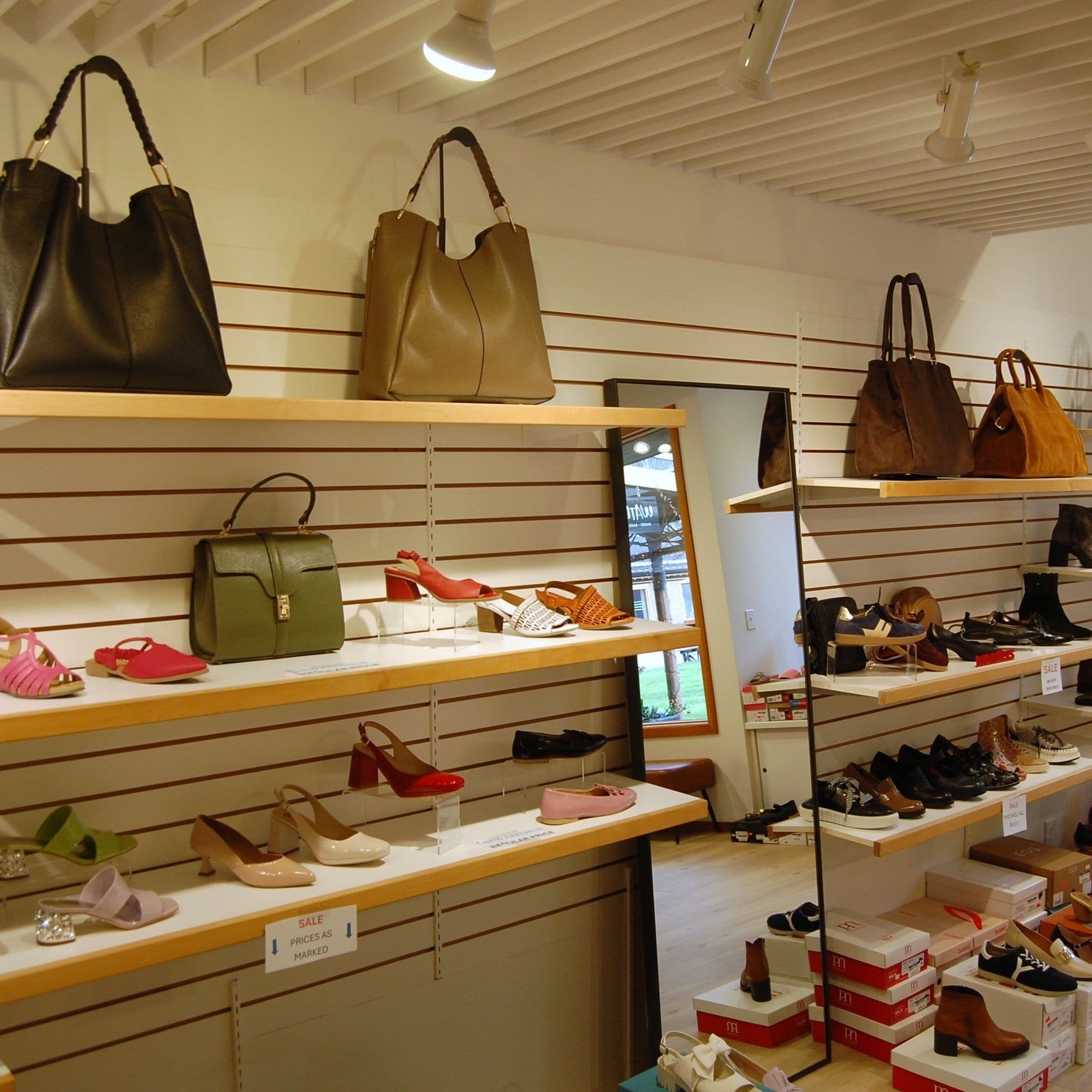 Shoe wall featuring a green tote and rows of pink, red and neutral shoes