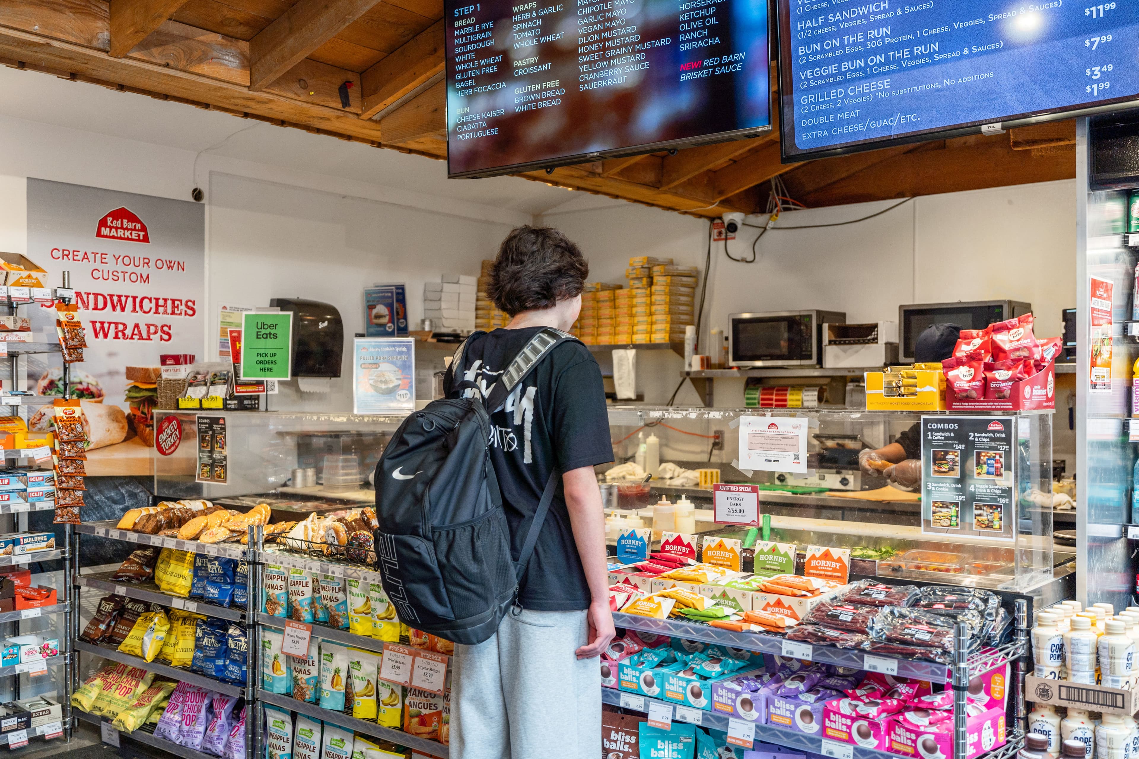 Customer at the sandwich and wrap counter reading the menu boards