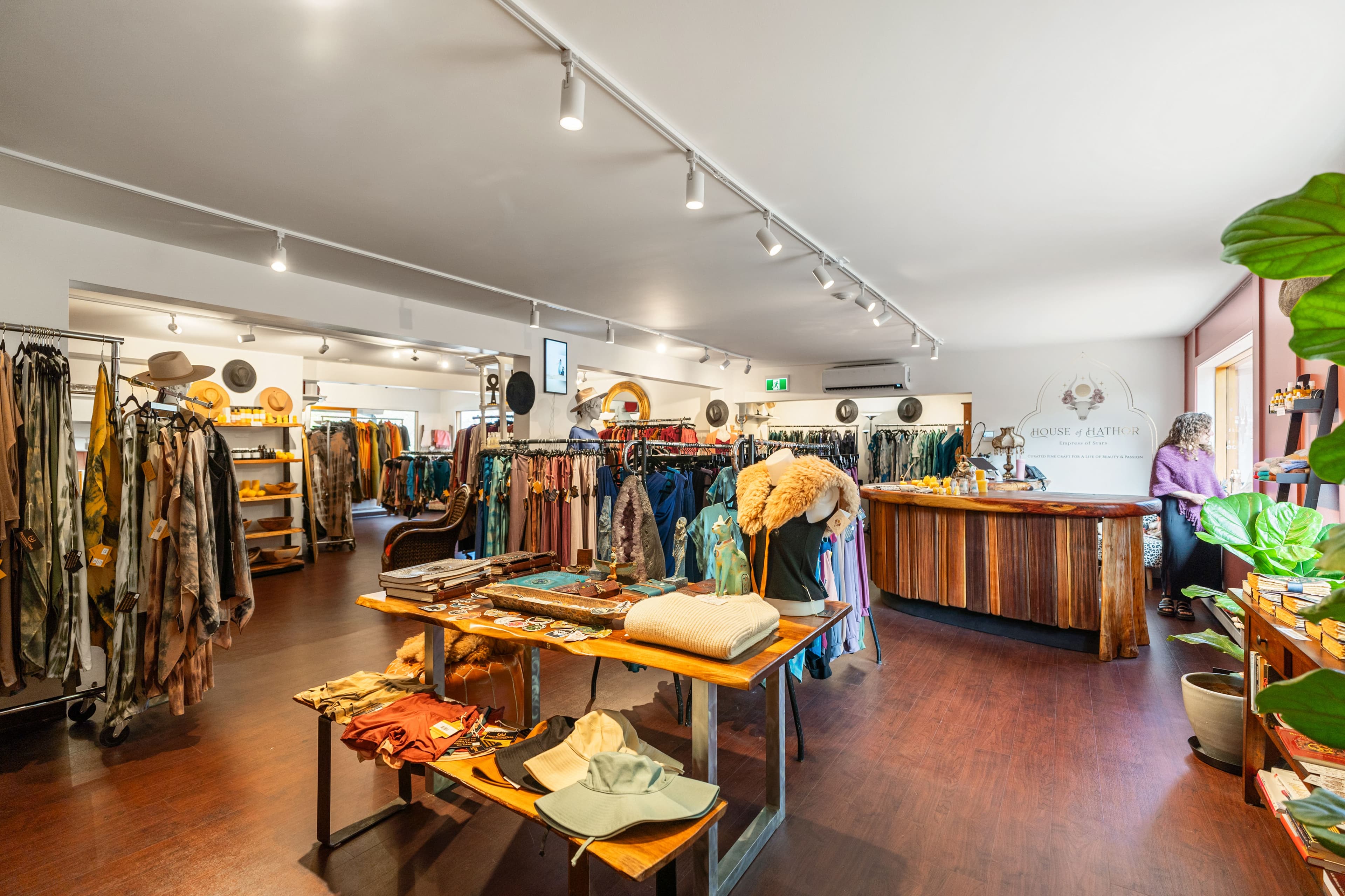 House of Hathor boutique interior with clothing racks and the wordmark on the back wall