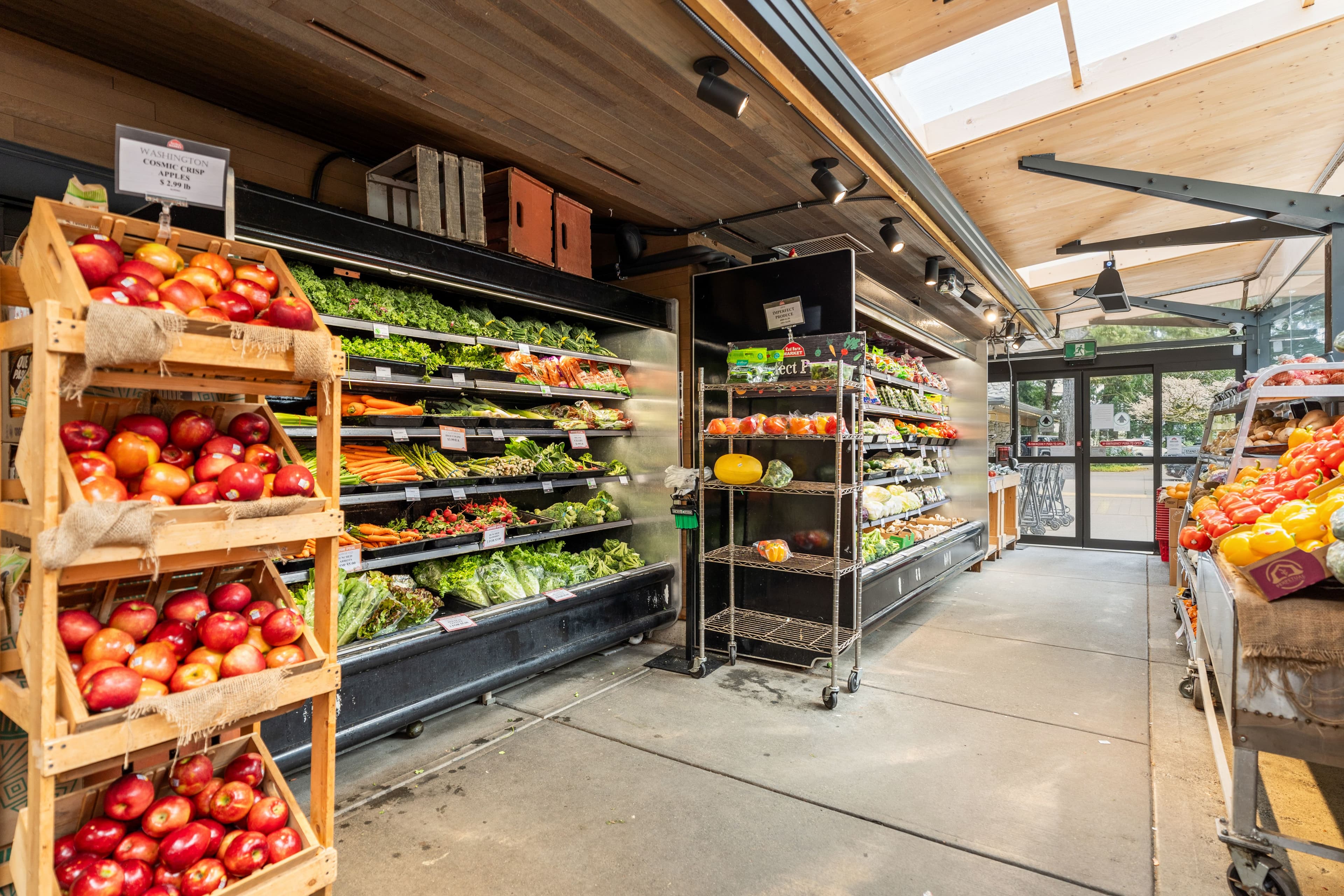 Apple crates and produce shelves with kale, carrots and peppers
