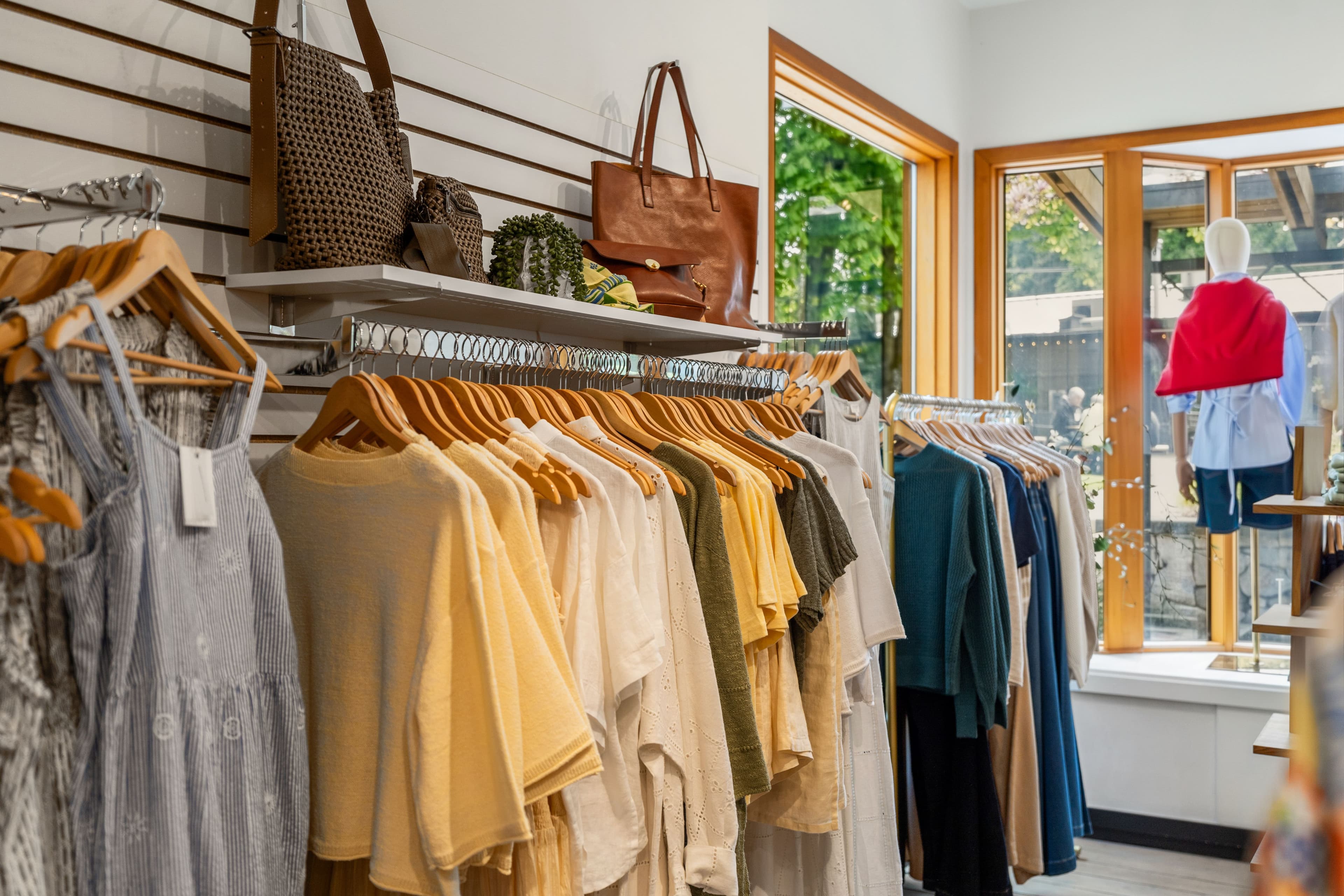 Pastel garment rack with handbags above and a styled mannequin visible through the window