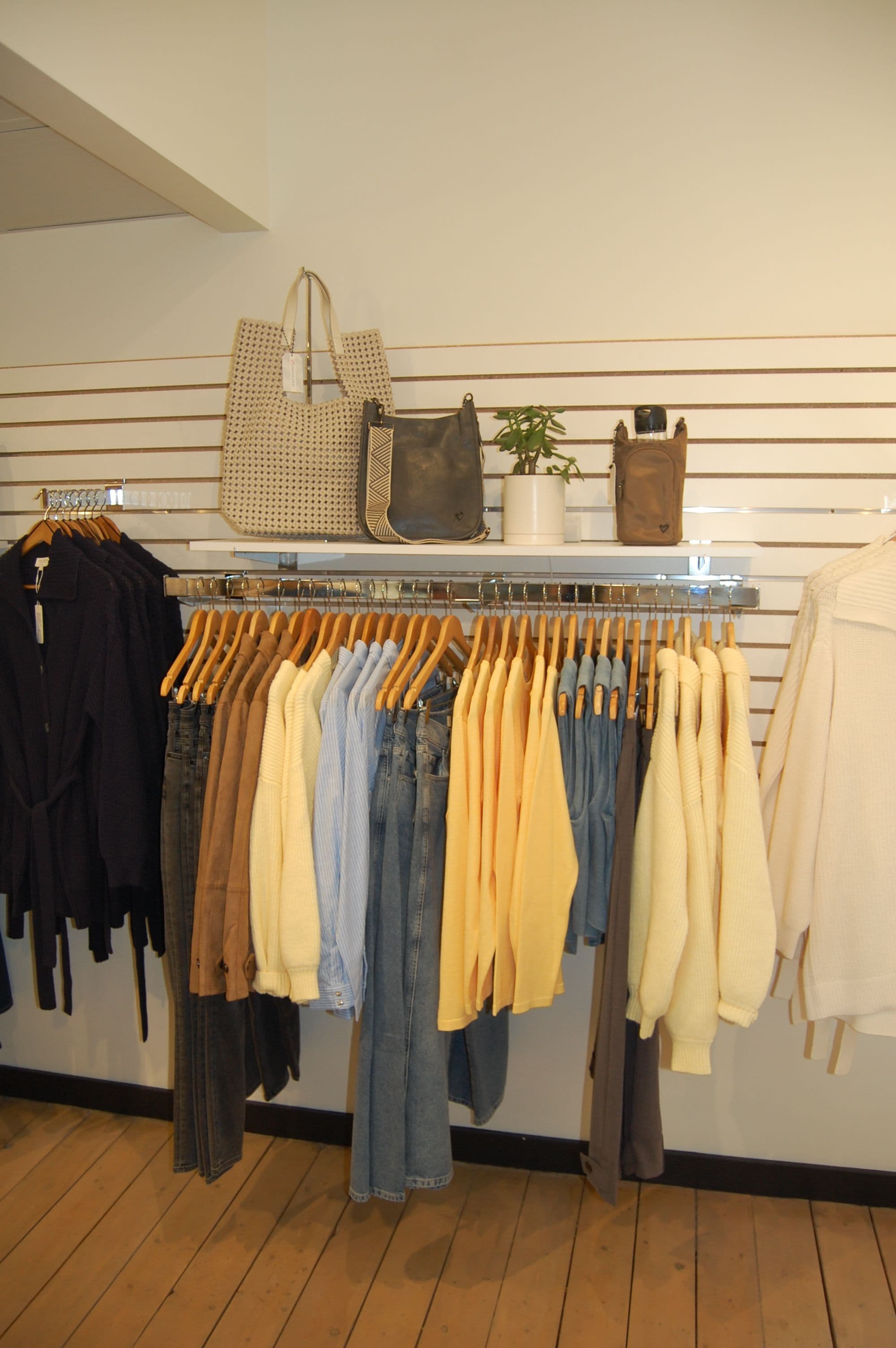 Garment rack with folded blues, yellows and whites stacked above