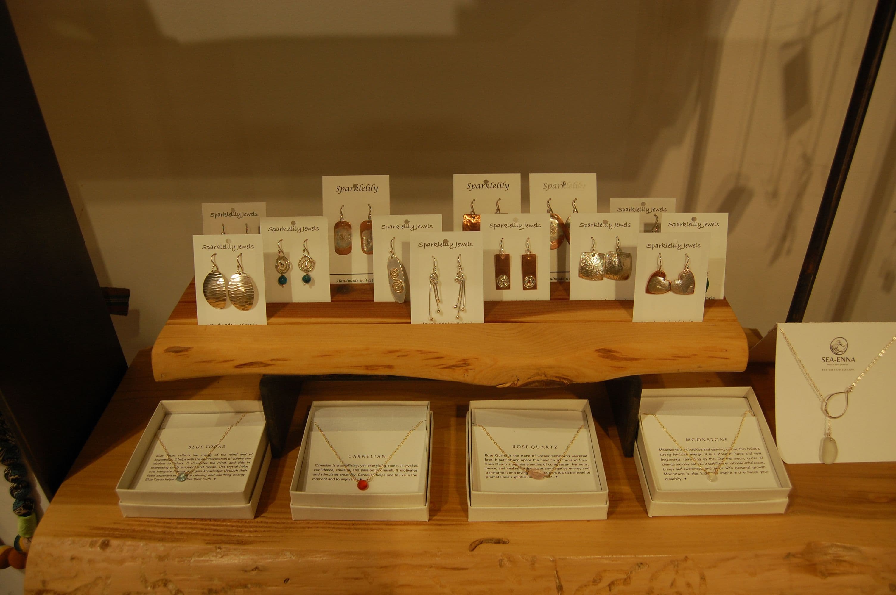 Sparkletely earring cards and small boxed necklaces on a wood shelf