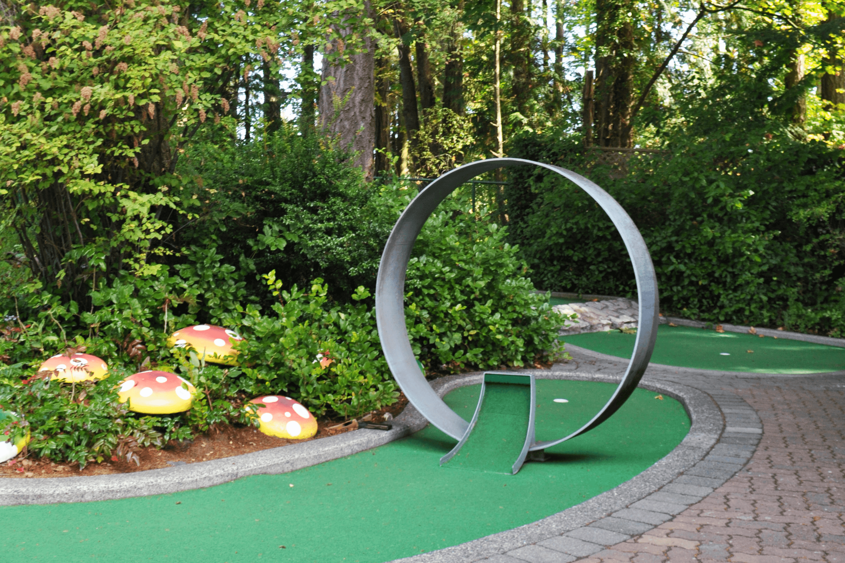 Whimsical course feature with red and white mushrooms beside a metal arc