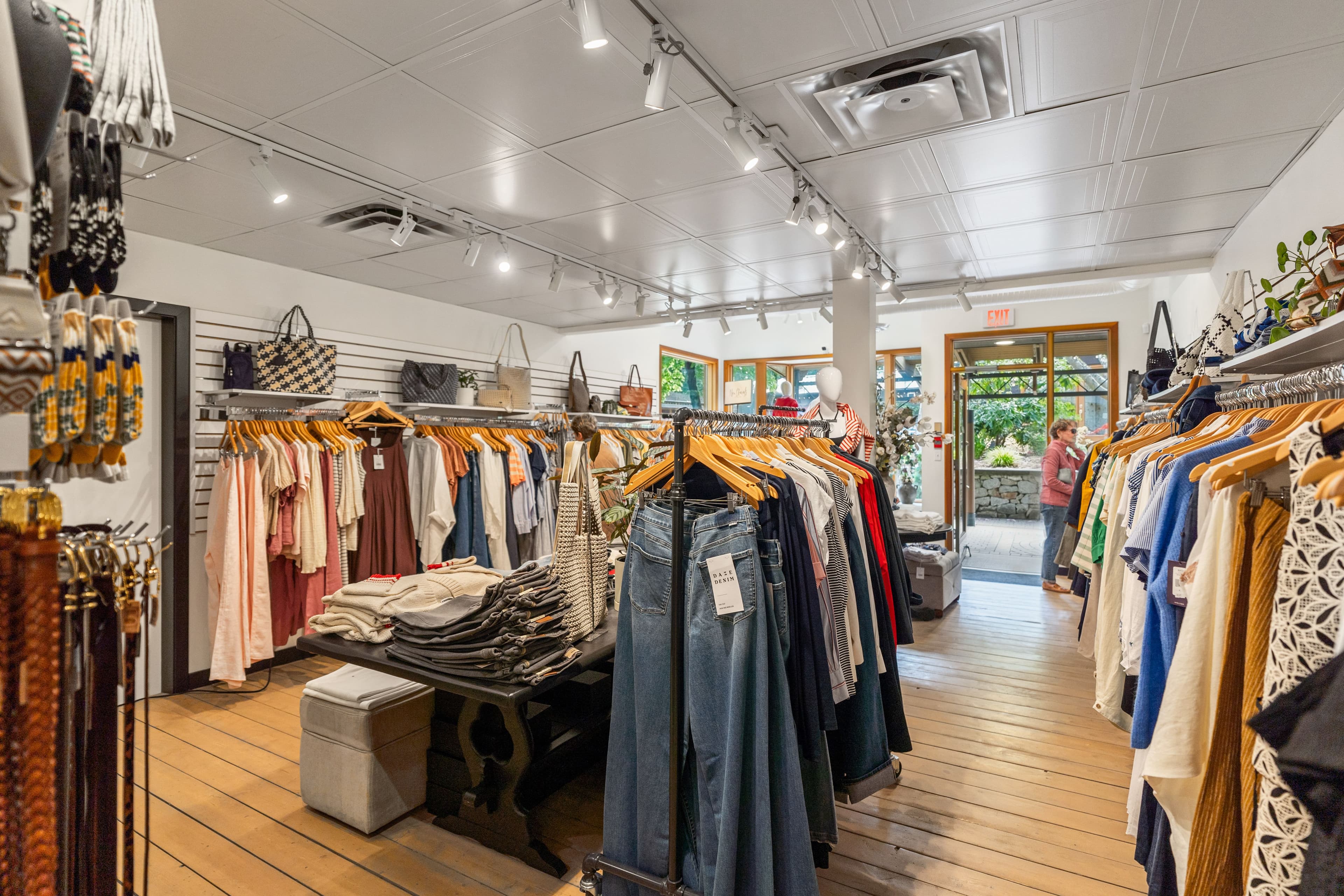 Wide view of Moden Boutique looking toward the open doorway with racks on both sides