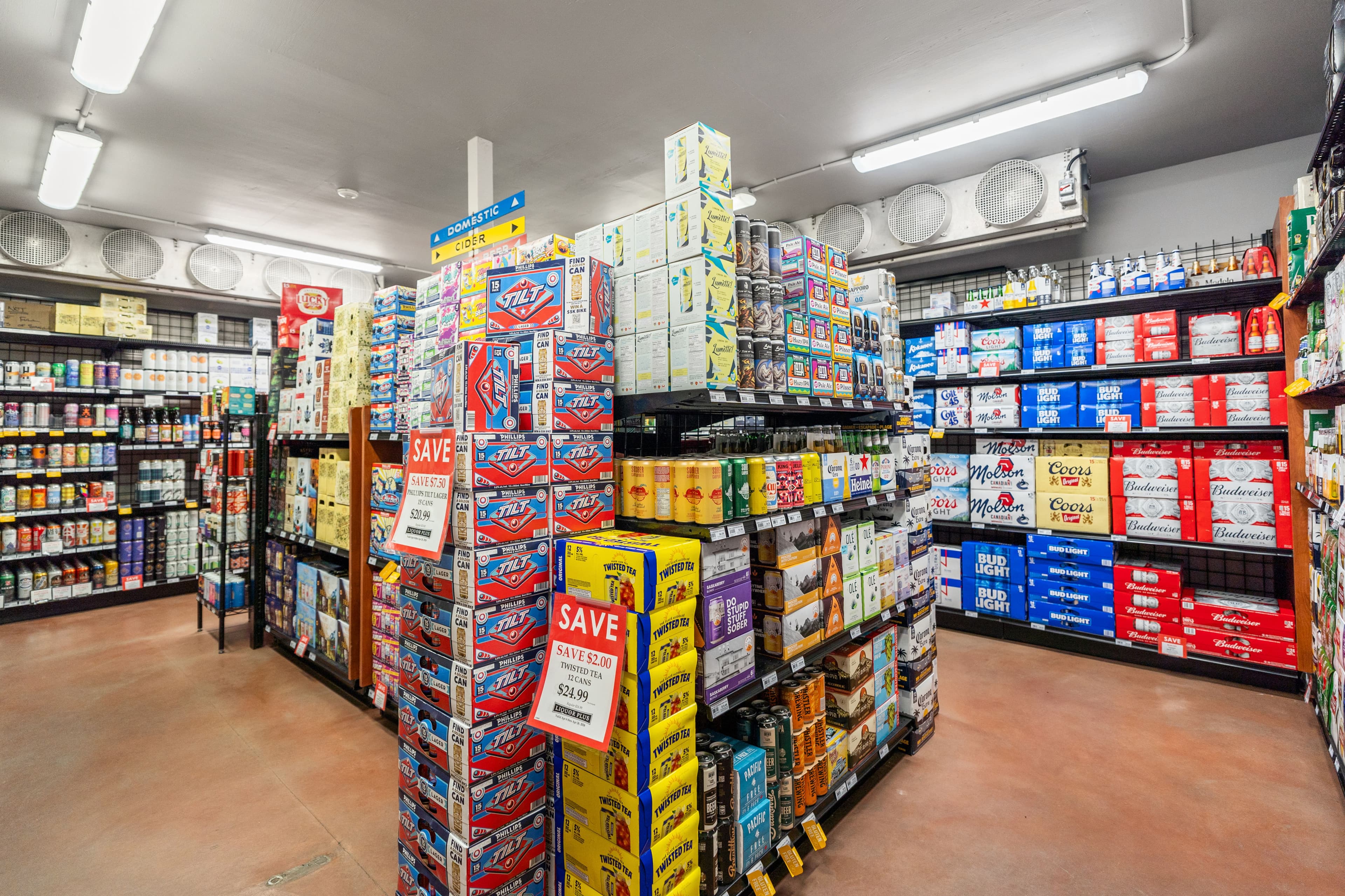 Beer and cider section with stacked cases and chilled doors