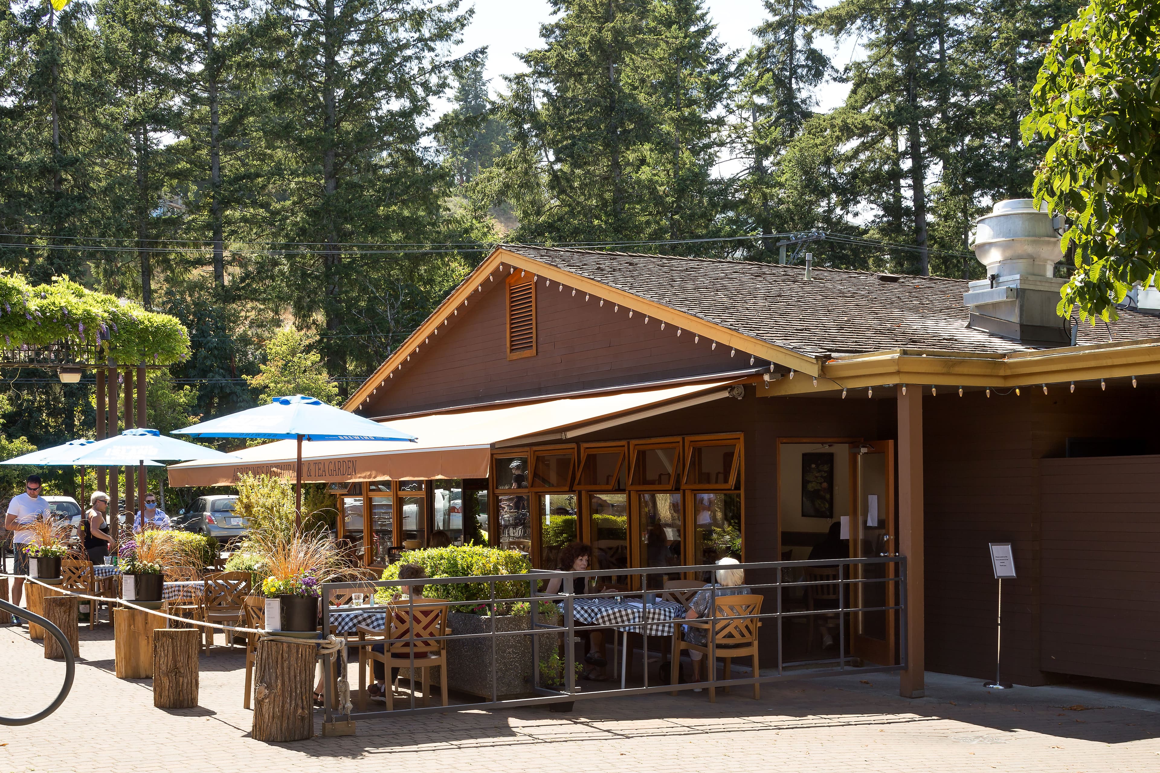 Adrienne's exterior with blue patio umbrellas under the trees