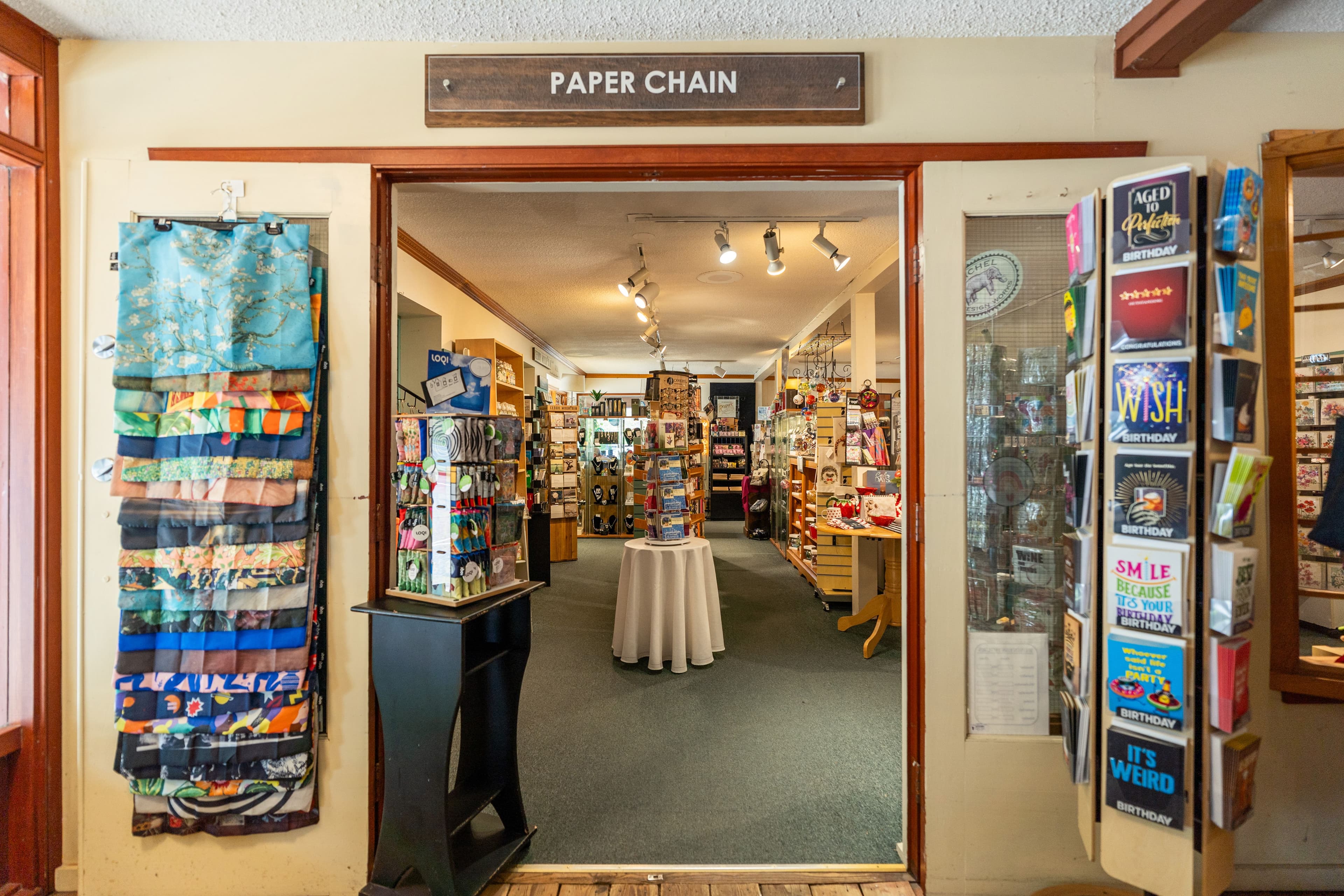Paper Chain entrance with branded sign and scarf and card displays flanking the doors