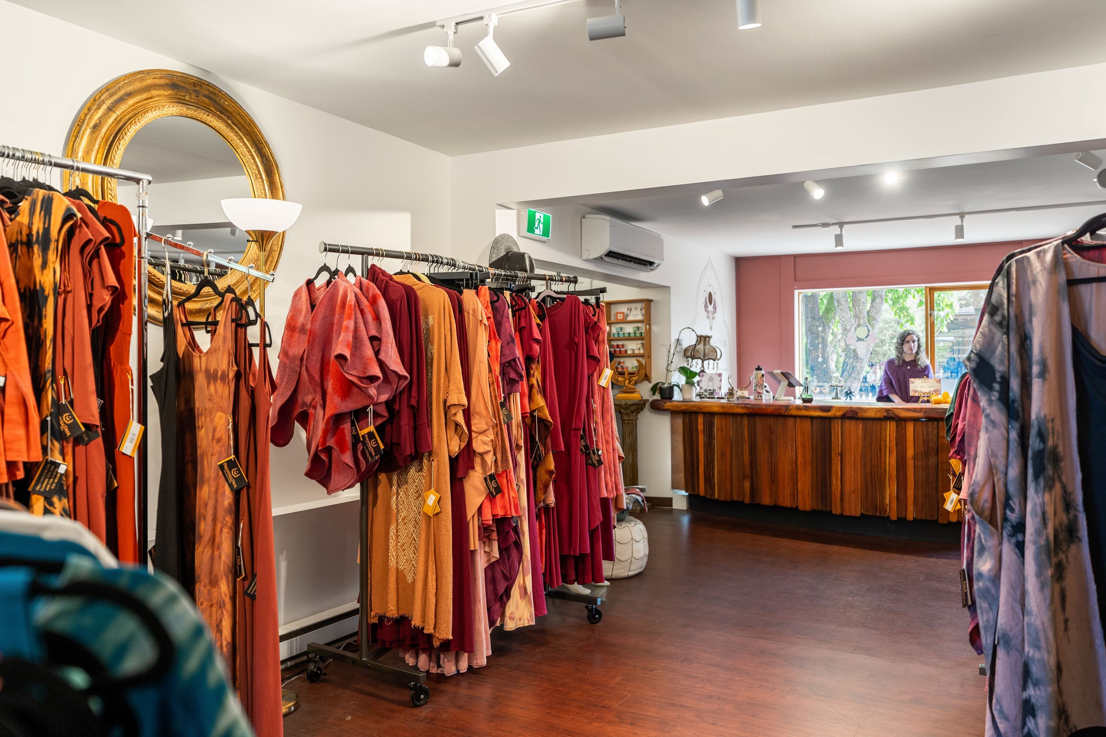 Warm-toned interior with red and burgundy garments and a gold mirror
