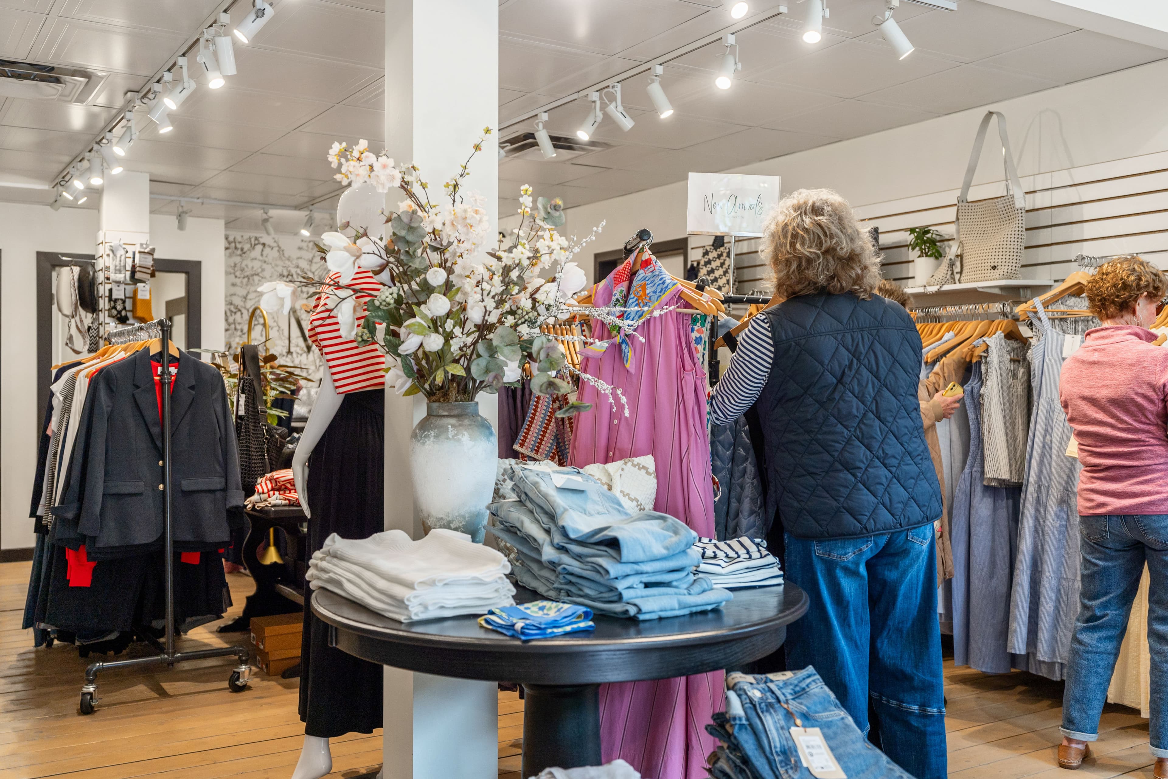 Two customers browsing styled garments with denim stacked on the centre table